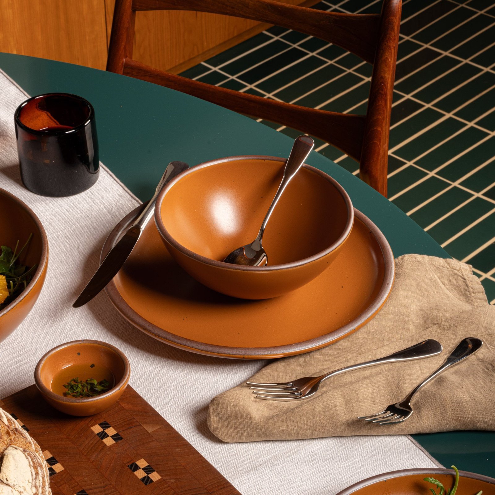 Vella Supply soup bowl in Ember, in a table setting with other dinnerware